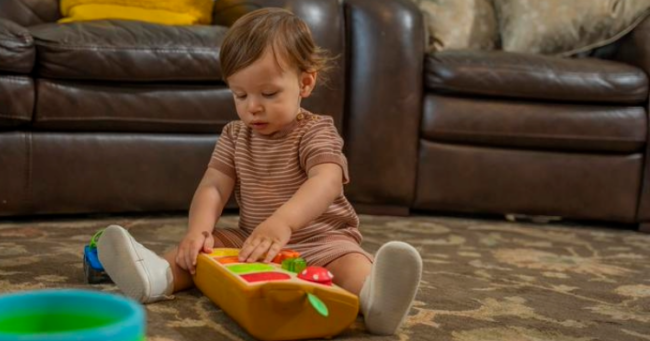 Toddler in striped shirt playing with wooden toys