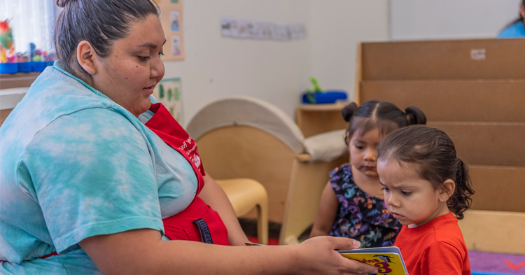 Child care provider in a classroom with two small children.